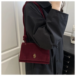 Detail of burgundy suede crossbody bag featuring a unique rope knot shoulder strap design