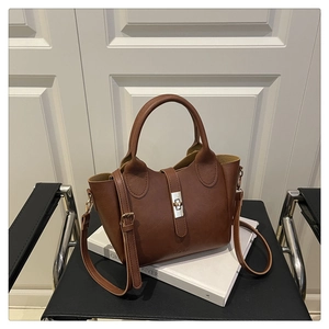 Detailed close-up of brown faux leather bucket bag with silver twist lock and strap
