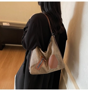 Side view of large khaki tote bag with dark brown leather details and zipper pockets
