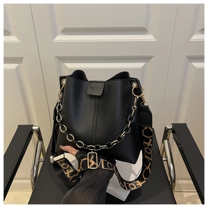 Detail of black pebbled leather bucket bag with Fashion embossing and wide textile strap