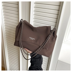 Detail of dark brown leather tote with chain strap and printed fashion logo lettering