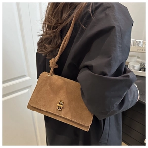 Detailed view of brown suede crossbody bag featuring a vintage gold interlocking ring buckle