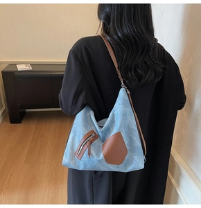 Detail of blue denim hobo bag with brown leather pockets and adjustable shoulder strap