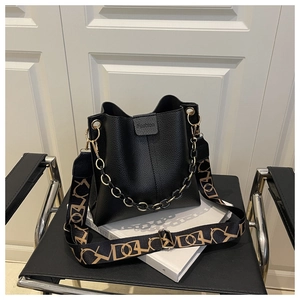 Detail of black pebbled leather bucket bag with chain strap and printed shoulder belt