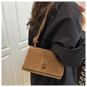 Detail of vintage brown suede shoulder bag with gold metal clasp and knotted strap design