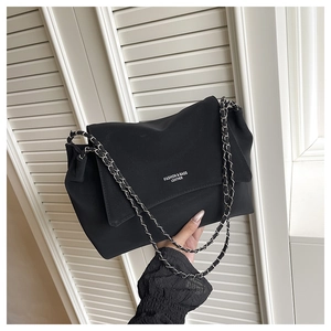 Close-up of black tote bag with silver chain strap and fashion lettering detail