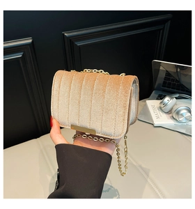 Close-up of quilted velvet texture and golden chain strap on a small crossbody bag