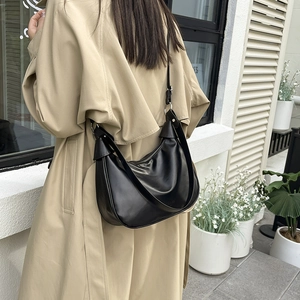 Minimalist black crescent hobo shoulder bag styled with a khaki trench coat for autumn