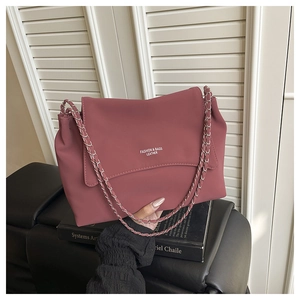 Detail of dusty pink chain shoulder bag with embossed text on matte leather surface