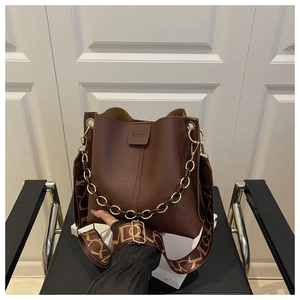 Detail of dark brown pebble leather bucket bag featuring fashion embossing and dual straps