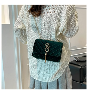 Detail of dark green velvet quilted bag with gold S logo tassel and chain strap