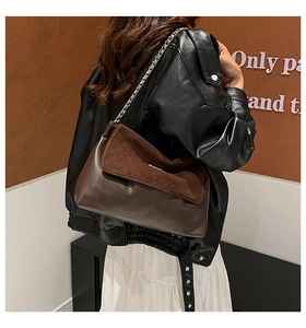 Detail of dark brown patchwork leather bag with golden chain strap on a model