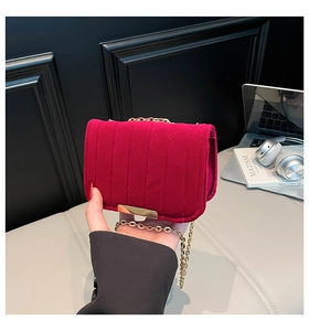 Detail of quilted dark rose velvet crossbody bag with gold chain strap and magnetic lock