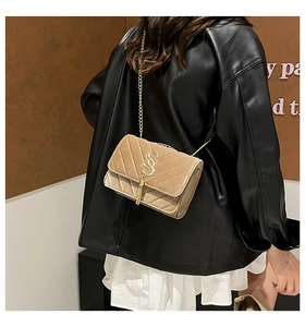 Detail of light brown suede shoulder bag with gold chain strap and stylish fringe tassel