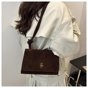 Detail of dark brown suede crossbody bag with gold twist lock and knotted strap