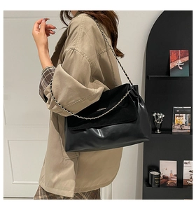 Detail of black patchwork shoulder bag with gold chain strap and high-quality leather texture