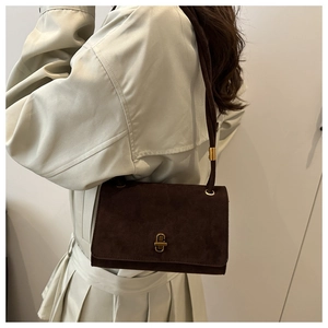 Detail of dark brown suede shoulder bag featuring a gold C-shaped rotating lock buckle