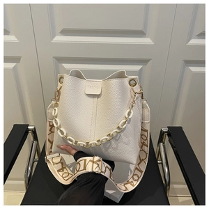 Detail of white lychee leather bucket bag with chain handle and patterned strap