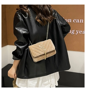 Detail of camel suede crossbody bag with V-quilt pattern and gold tassel hardware