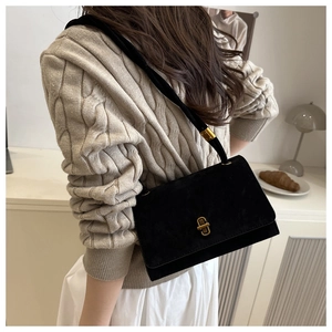Close-up of black matte suede shoulder bag featuring a sleek gold metal buckle detail
