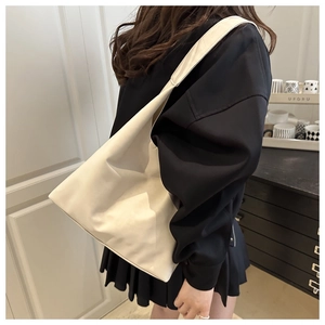 Close-up of minimalist cream white tote bag with soft matte leather texture worn on shoulder