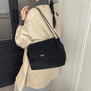 Sac bandoulière minimaliste en cuir noir porté par un modèle avec lettrage mode