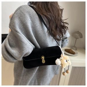 Détail d'un sac à bandoulière en daim noir avec fermoir doré et pendentif en peluche