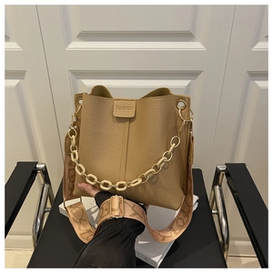 Detail of camel bucket bag with textured leather, resin chain, and woven strap