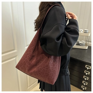 Side view of a vintage burgundy leopard print tote bag worn on a model's shoulder