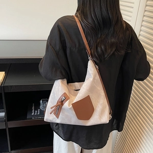 Minimalist beige tote bag with brown leather details shown on model in home setting
