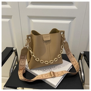 Detail view of beige lychee leather bucket bag with resin chain and patterned strap