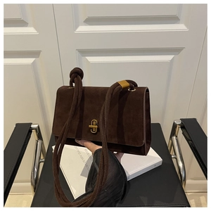 Detailed view of dark brown suede shoulder bag with rotating metal lock and rope strap