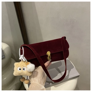 Detail of burgundy velvet shoulder bag featuring golden clasp and plush toast charm