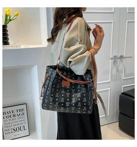 Dettaglio della borsa shopper nera con orsetti, manici in pelle marrone e coulisse laterali