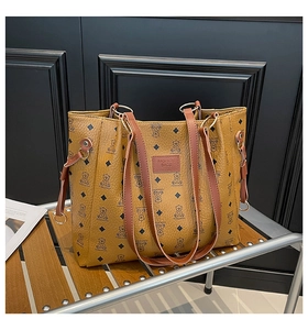 Dettaglio della grande borsa tote color cammello con motivo a orso e pelle martellata