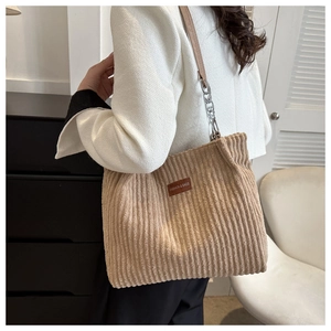 Close-up of light brown corduroy tote bag featuring a leather patch and chain strap