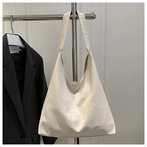 Detail of off-white minimalist tote bag with wide strap on a sleek metal display stand