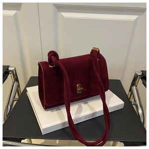 Detail of burgundy suede shoulder bag with vintage gold clasp and knot strap design