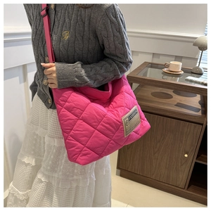 Détail du sac cabas matelassé fuchsia avec finition texturée et écusson de mode design