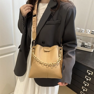 Elegant beige bucket bag with gold chain strap and patterned wide shoulder strap