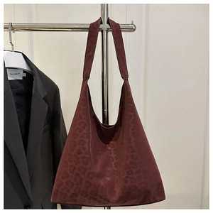 Detail view of burgundy leopard print tote bag with matte texture and wide shoulder strap