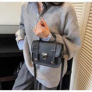 Detail of vintage black leather crossbody bag with silver buckles on a model