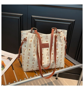 Dettaglio della borsa tote beige vintage con orsetti e manici marroni su panca