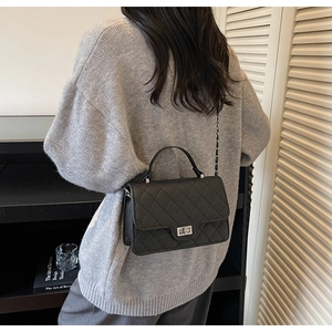 Detailed view of black quilted crossbody bag with silver chain strap and metal lock