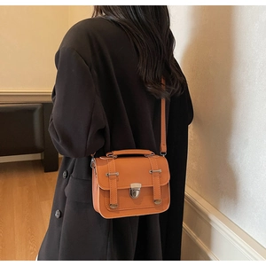 Rear view of a model wearing the brown vintage small crossbody bag with silver buckle detail