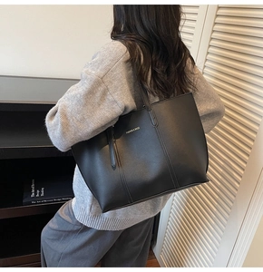 Vue détaillée d'un grand cabas en cuir noir porté à l'épaule par un mannequin