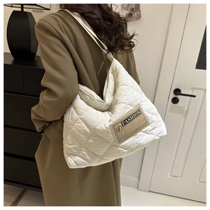 Détail du sac cabas blanc matelassé avec étiquette de mode brune et sangle ajustable