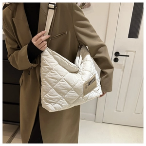 Détail du sac cabas matelassé blanc avec bandoulière réglable porté sur un blazer marron