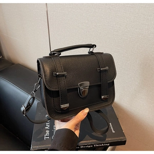 Close-up of black retro small square bag with metallic buckle and round handle