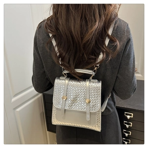 Silver woven backpack with metallic texture and polished leather flap shown on model